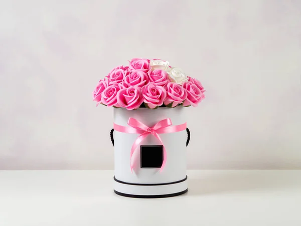 Букет розовых и белых роз, украшенных в шляпной коробке на светлом фоне . — стоковое фото