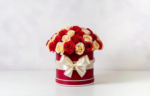 Un ramo de rosas rosadas y blancas decoradas en una caja de sombreros sobre un fondo claro . — Foto de Stock