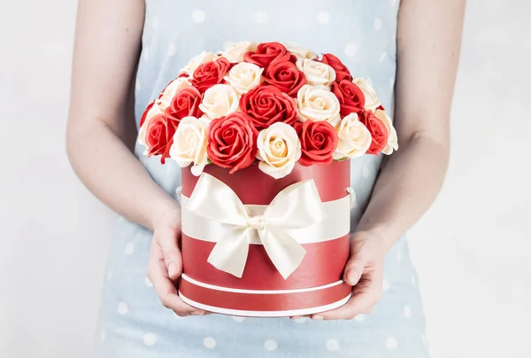Decoración de la boda: la chica en un vestido de globo sostiene una caja redonda con un ramo de rosas rojas y blancas . — Foto de Stock