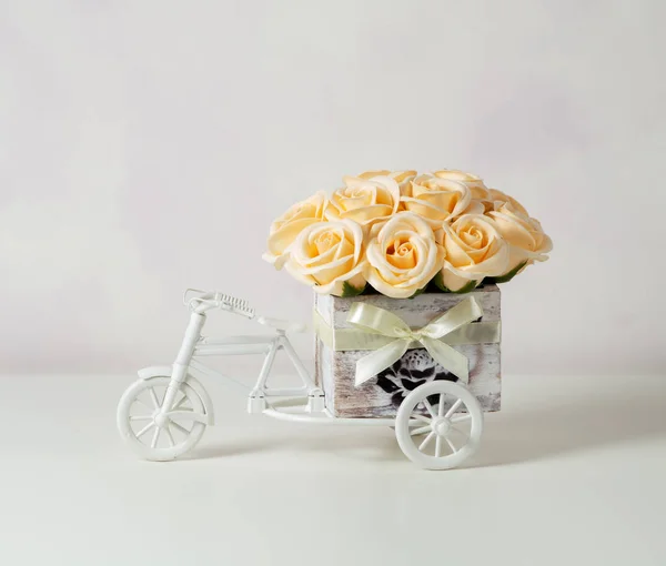 Un ramo de rosas amarillas en una pequeña caja decorativa de madera en forma de bicicleta sobre un fondo claro. Diseño vintage . — Foto de Stock