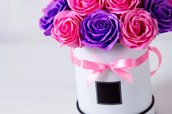 Ramo de rosas rosadas y moradas en una caja de sombrero blanco sobre un fondo claro . —  Fotos de Stock