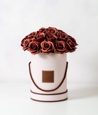 Çiçek dekorasyon: beyaz zemin üzerine beyaz şapka kutusunda kahverengi gül buketi.