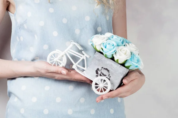 Decoración de la boda hecha a mano: La niña sostiene un pequeño ramo de rosas en sus manos en una caja decorativa en forma de bicicleta. Primer plano de las manos . — Foto de Stock