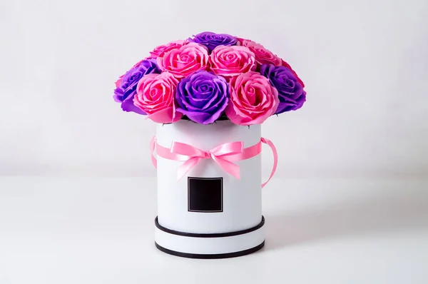 Ramo de rosas rosadas y moradas en una caja de sombrero blanco sobre un fondo claro . — Foto de Stock