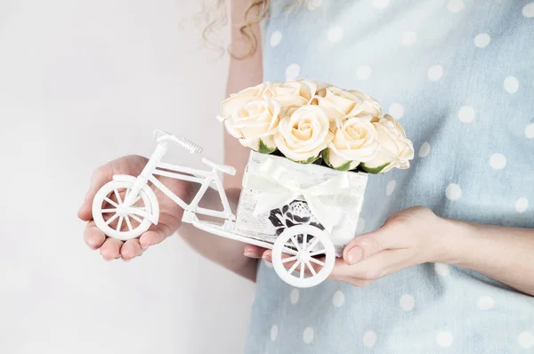 Kézzel készített dekoráció esküvő: A lány egy kis csokor Rózsa tart a kezében egy dekoratív dobozban egy kerékpár formájában. Közeli kép a kezek. — Stock Fotó