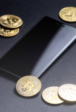 Kripto-para kazanç: altın paralar bitcoin ve karanlık bir arka plan üzerinde smartphone. Dikey vurdu. Yakın çekim.