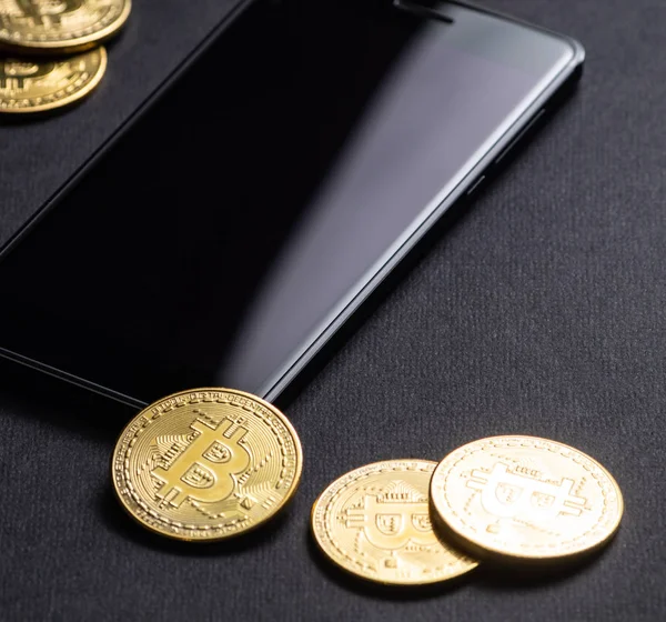 暗号通貨の収益 Bitcoin と暗い背景にスマート フォンの金貨 正方形のフレーム クローズ アップ — ストック写真