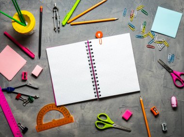 Okul malzemeleri okul için: Not defteri, kalemler, pembe cetvel, gri bir tablo üzerinde dağınık pergel. Üstten görünüm. Kopya alanı.