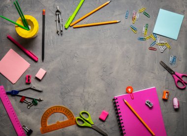 Okul malzemeleri okul için: Not defteri, kalemler, pembe cetvel, gri bir tablo üzerinde dağınık pergel. Üstten görünüm. Kopya alanı.
