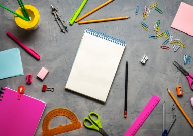 Okul malzemeleri okul için: Not defteri, kalemler, pembe cetvel, gri bir tablo üzerinde dağınık pergel. Üstten görünüm. Kopya alanı.