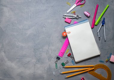 Okul malzemeleri okul için: Not defteri, kalemler, pembe cetvel, gri bir tablo üzerinde dağınık pergel. Üstten görünüm. Kopya alanı.