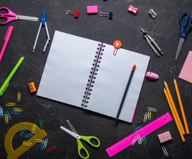 Okul malzemeleri okul için: Not defteri, kalemler, pembe cetvel, gri bir tablo üzerinde dağınık pergel. Üstten görünüm. Kopya alanı.