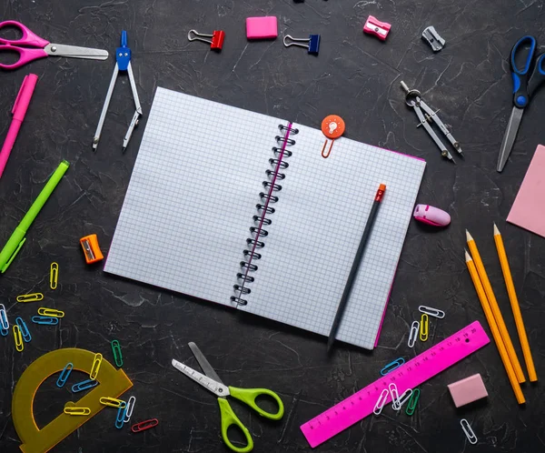 Okul malzemeleri okul için: Not defteri, kalemler, pembe cetvel, gri bir tablo üzerinde dağınık pergel. Üstten görünüm. Kopya alanı.