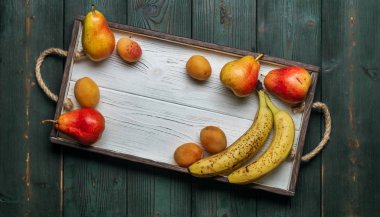 Beyaz ahşap tepsi üzerinde taze otantik meyve: banatas, armut, kayısı. Kırsal ayar. Üstten görünüm. Kopya alanı