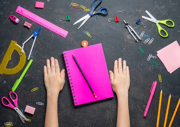 Okula geri: Kırtasiye ve karanlık bir tablo çocuk elleri. Üstten görünüm.