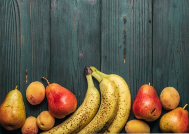 Detoks: taze olgun muz, armut ve kayısı yeşil ahşap bir masa üzerinde saçılma. Kopya alanı ile çerçeve.