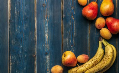 Detoks: taze olgun muz, armut ve kayısı ahşap bir mavi masa üzerinde saçılma. Kopya alanı ile çerçeve.