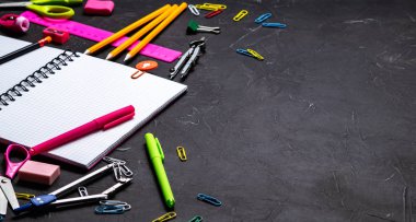 Okul malzemeleri okul için: Not defteri, kalemler, pembe cetvel, gri bir tablo üzerinde dağınık pergel. Üstten görünüm. Kopya alanı.