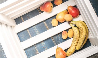 Sağlıklı gıda: Olgun taze muz, armut, kayısı bir ahşap kutu dibinde. Kopya alanı