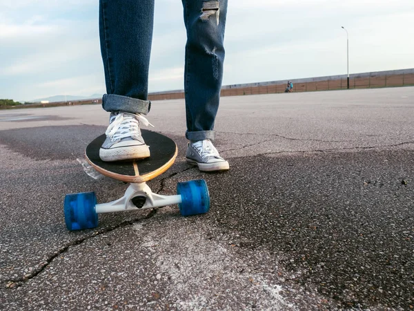 Straat sport: Close-up van pintail longboard en benen van een meisje in sneakers en jeans. — Stockfoto