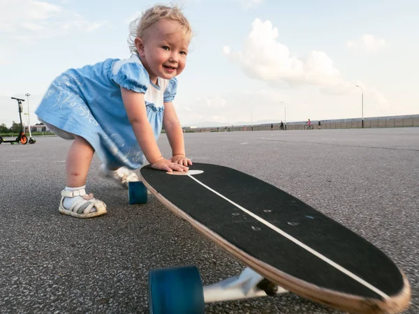 Straat Sport: Gelukkig meisje in het berijden van een longboard op de stoep en plassen. — Stockfoto
