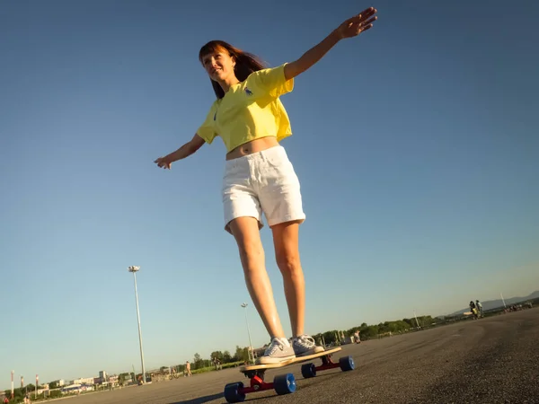 Straat sport: Een meisje in een helder geel T-shirt is rollen op een longboard op het asfalt van de stad. — Stockfoto