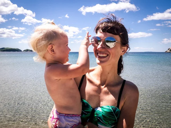 Отдых на море: моя мама в солнечных очках с ребенком на песчаном пляже. Крупный план . — стоковое фото