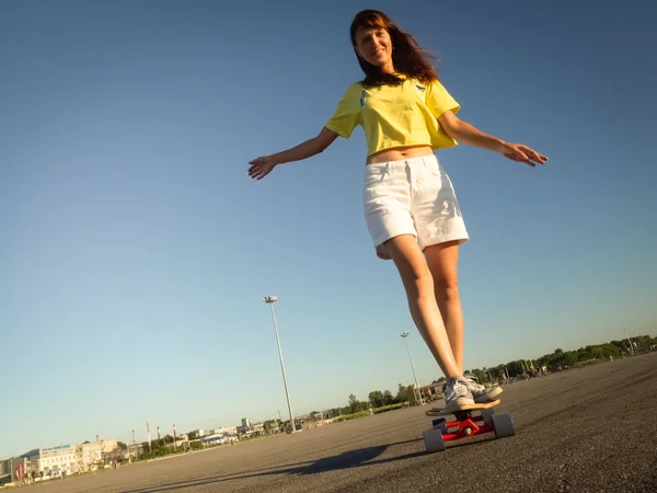 Straat sport: Een meisje in een helder geel T-shirt is rollen op een longboard op het asfalt van de stad. — Stockfoto