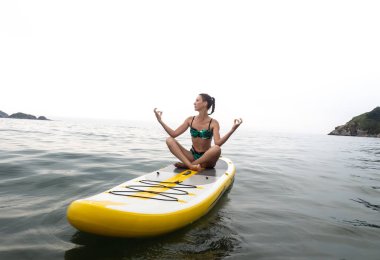 Denizde tatil: kız ve yelken sarı bir sup gemide bir lotus bulunduğu derin derin düşünür.
