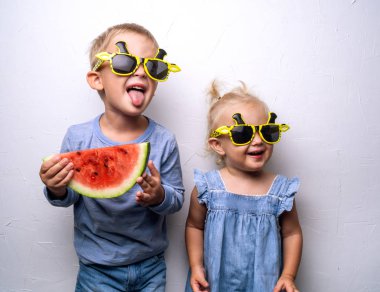 Mutlu erkek ve kız sarı güneş gözlüğü on beyaz duvar hayranıyım kırmızı karpuz yemek. Portre.