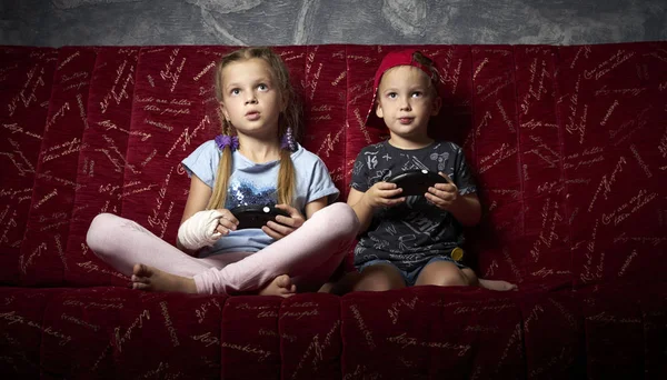 Computerspelletjes: een jongen en een meisje spelen van een game console in het donker en gamepads in hun handen houden. — Stockfoto