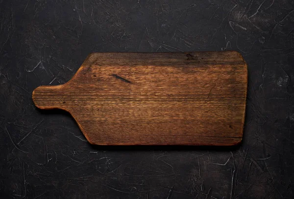 Empty old cutting board on a black background. Layout for the recipe. — Stock Photo, Image