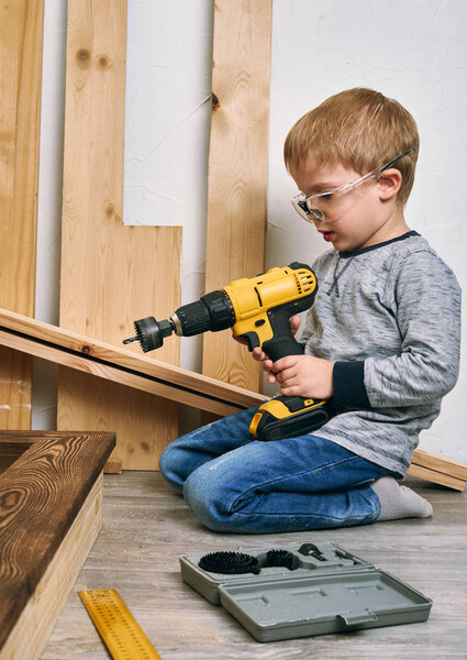 Семейное время: папа показывает сыну ручные инструменты, жёлтую отвертку и ножовку. Им нужно капать и капать доски для ремонта
.