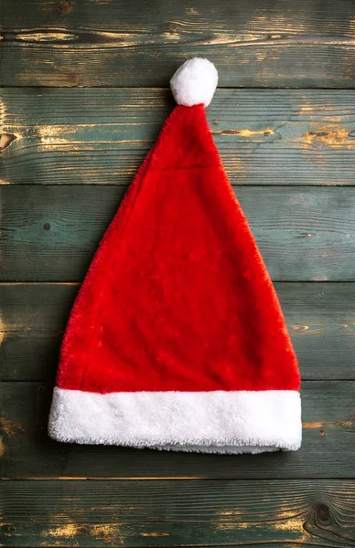 Red Santa Claus pălărie pe un fundal verde din lemn . — Fotografie, imagine de stoc