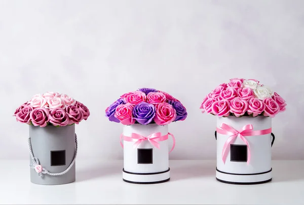 Flores como regalo: Tres ramos de rosas en cajas redondas sobre fondo blanco . — Foto de Stock
