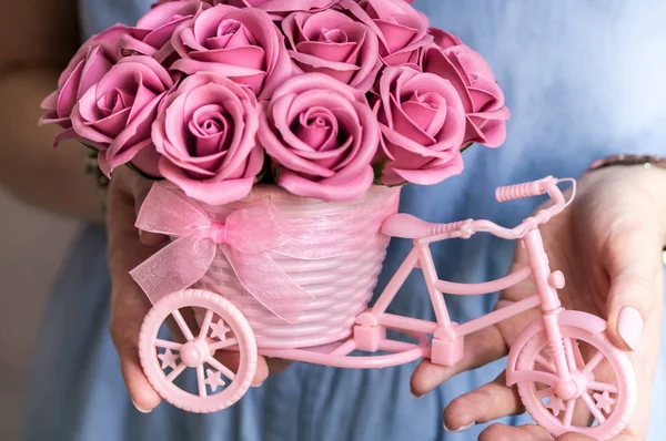 Decoración floral festiva: una pequeña canasta decorativa en forma de tenedor con capullos de flores rosadas en las manos de una niña . — Foto de Stock