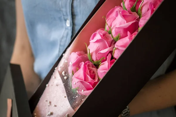 Floristas trabajan: Una chica demuestra una caja con un ramo de rosas rosadas . —  Fotos de Stock