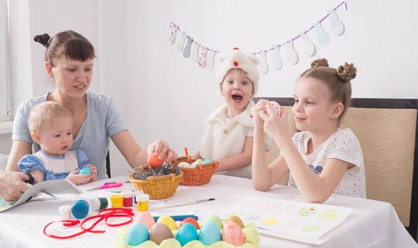 Påskhögtiden: Familjen målar påskägg vid bordet. — Stockfoto