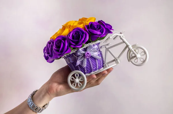 Decoración floral festiva: una pequeña cesta decorativa en forma de forbike con brotes de flores púrpura y amarilla . — Foto de Stock