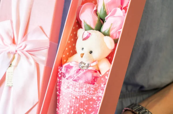 Floristas trabajan: Una chica demuestra una caja con un ramo de rosas rosadas y un oso de peluche . — Foto de Stock