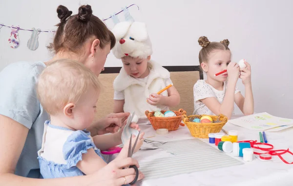 Festival de Páscoa: A família na mesa se preparar para o feriado. Filha colocou um padrão no ovo . — Fotografia de Stock