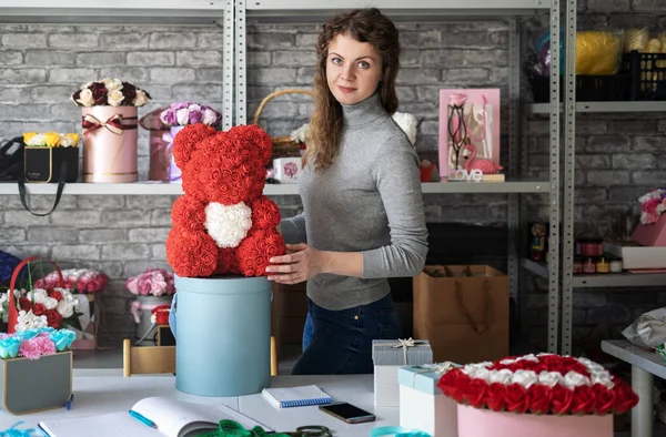 Flower shop: çiçekçi kız küçük kırmızı gül bir oyuncak ayı gösterir. Atölye ve bir çok farklı çiçek buketleri çevresinde.