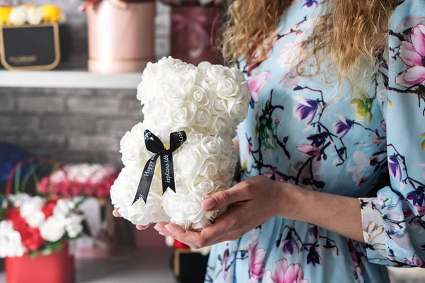 Floristería: Floristería muestra un osito de peluche de pequeñas rosas blancas. Alrededor del taller y un montón de diferentes ramos florales . — Foto de Stock