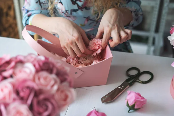 Floristería: una floristería recoge un ramo de capullos de rosa en una canasta de papel . — Foto de Stock