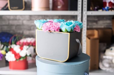 Flower shop: mavi gül ve gri bir kutu içinde pembe karanfil küçük bir buket.