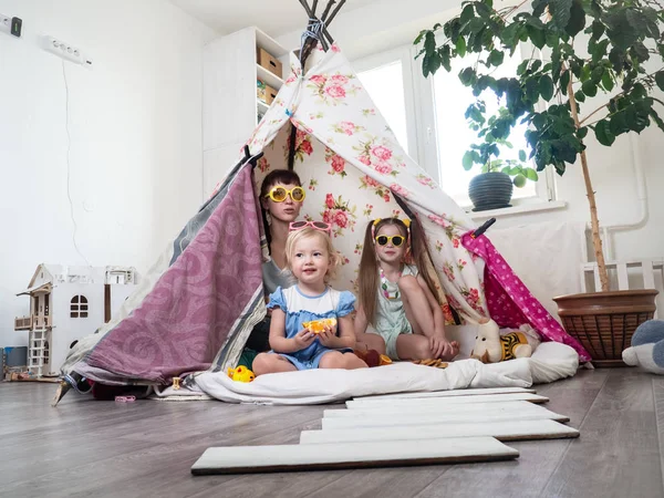 家族の時間: ママと子供の自家製テントの姉妹の子ども遊びを自宅の一部. — ストック写真
