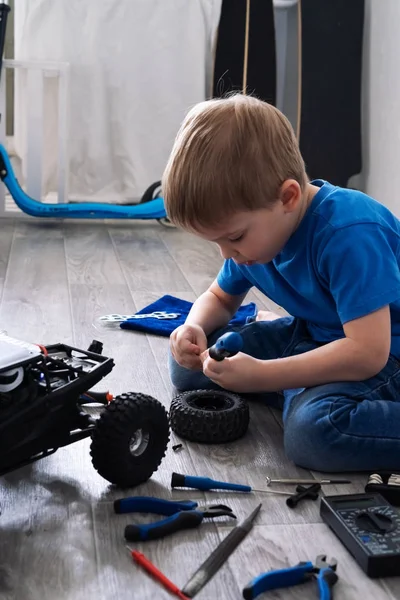 Auto modelagem: menino reparando um modelo de carro controlado por rádio em casa . — Fotografia de Stock