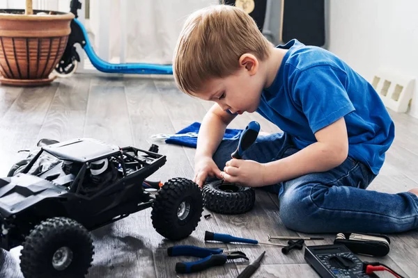 Auto modelagem: menino reparando um modelo de carro controlado por rádio em casa . — Fotografia de Stock