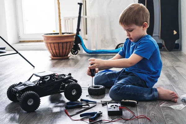 Auto modelagem: menino reparando um modelo de carro controlado por rádio em casa . — Fotografia de Stock