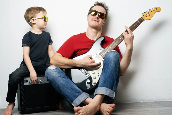 Happy father and little son playing guitar together